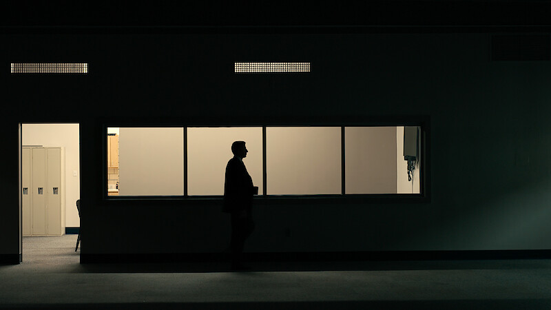 A shadowy figure stands in a dimly lit room.