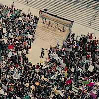 A shot from above of a crowd of political protestors on the steps of a government building.