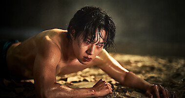 Kim Sung-Cheol as Jung Jinsu crawls on the ground shirtless in an image from 'Hellbound' Season 2.