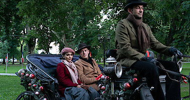 Woman and man ride in a horse and carriage in the park.