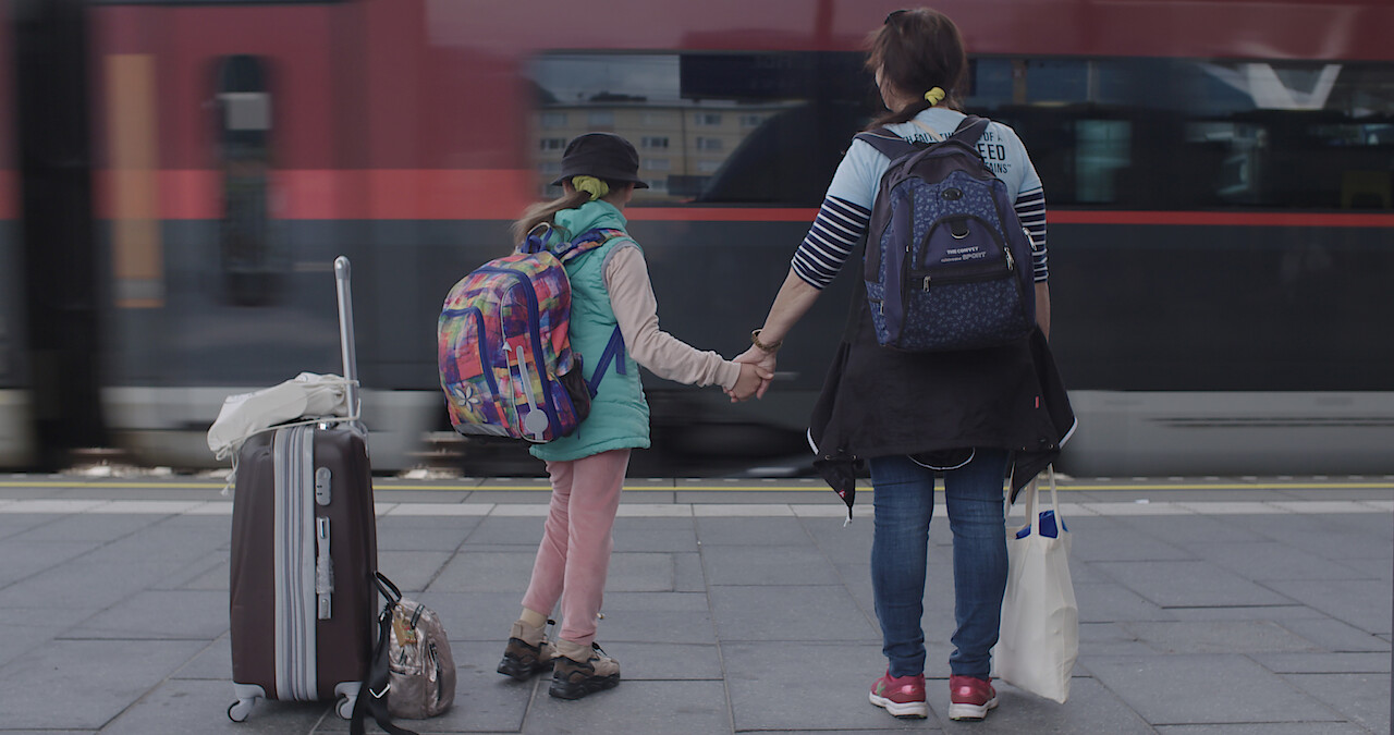 Milana and Olga wait for a train in Camp Courage.