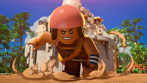 LEGO character in dynamic running pose, wearing a helmet and armband, stirring up dust in a bright outdoor jungle setting with a large stone monument and trees in the background.