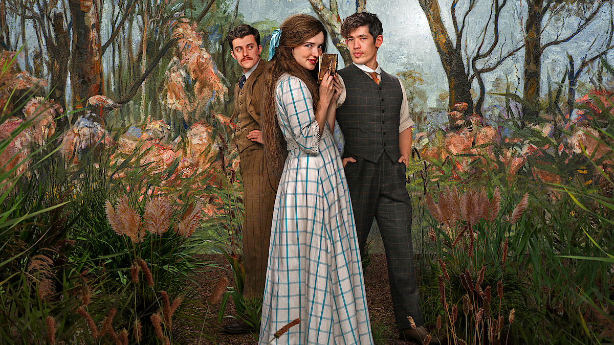 Three people in vintage clothing stand among tall grasses in a lush, painted woodland setting; the central woman in a checked dress is flanked by two men in period suits, all posing dramatically.