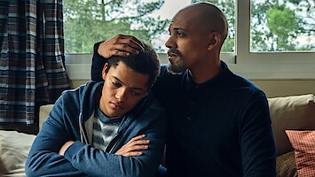 A father and son share a moment together while seated. 