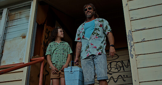two people standing on the porch of a dilapidated house. 