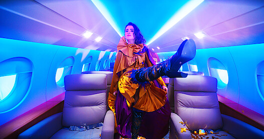 Laura Marano as Cami kicks her leg out inside of a plane.