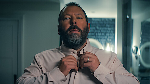 Bert Kreischer as Bert Kreischer buttoning up a shirt 'Free Bert.'