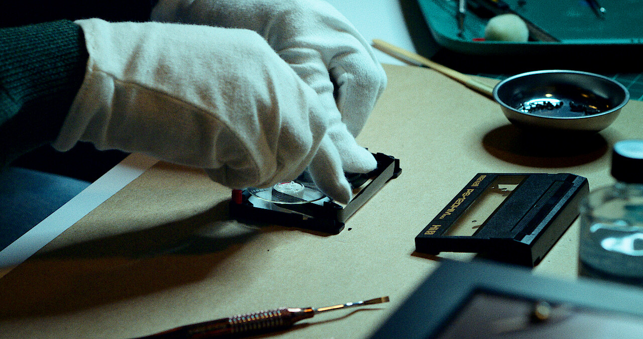 A close up of a character's hands working to restore video footage.