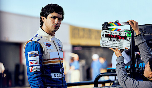 Ayrton Senna (Gabriel Leone) wears a white and blue racing suit behind the scenes of Senna.