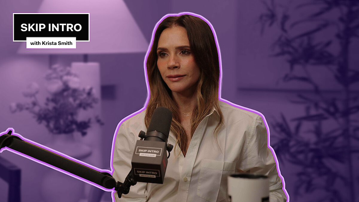 Victoria Beckham in a white shirt speaks into a microphone during a podcast interview, sitting in a softly lit studio with plants and a lamp, mood is calm and focused, overlay text reads "Skip Intro with Krista Smith".