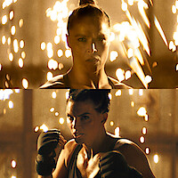 Ronda Rousey and Gina Carano with intense expressions face forward in a dramatic, dimly lit environment with sparks flying in the background, both wearing athletic gear and preparing to fight.