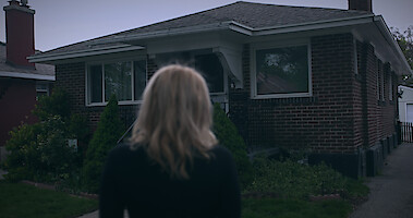 A woman in the foreground looks at a house.