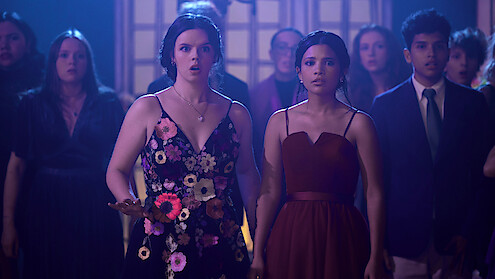 Ellie O’Brien as Grace and Nikki Rodriguez as Jackie wearing dresses in a crowd in 'My Life with the Walter Boys' Season 2.