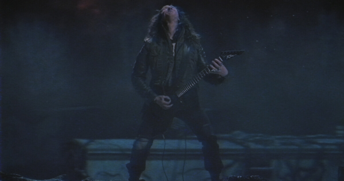 Eddie Munson playing guitar in a night scene.