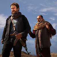 Gerard Butler stands in front of a man in an image from Kandahar. 