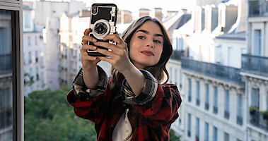 Emily Cooper (Lily Collins) takes a selfie with the rooftops of Paris in the background