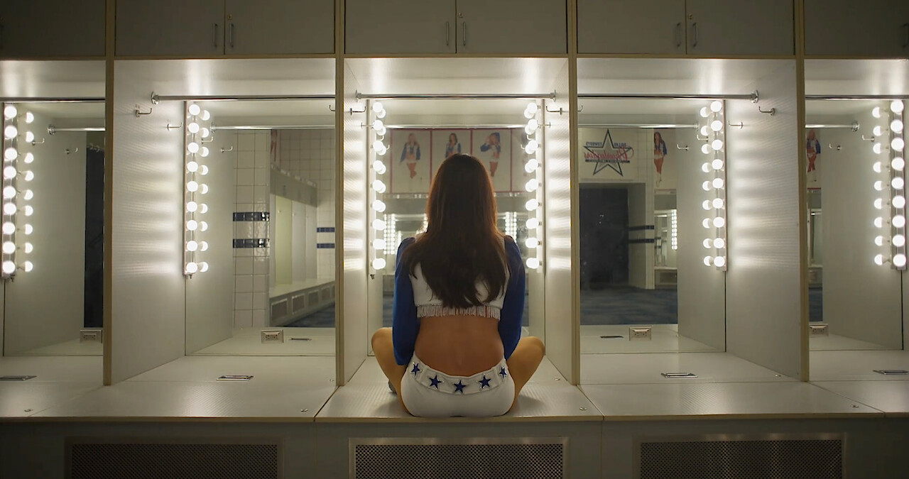 A Dallas Cowboys Cheerleader looking into a mirror.