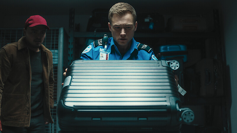 Taron Egerton as Ethan Kopek inspecting a suitcase in 'Carry On.'