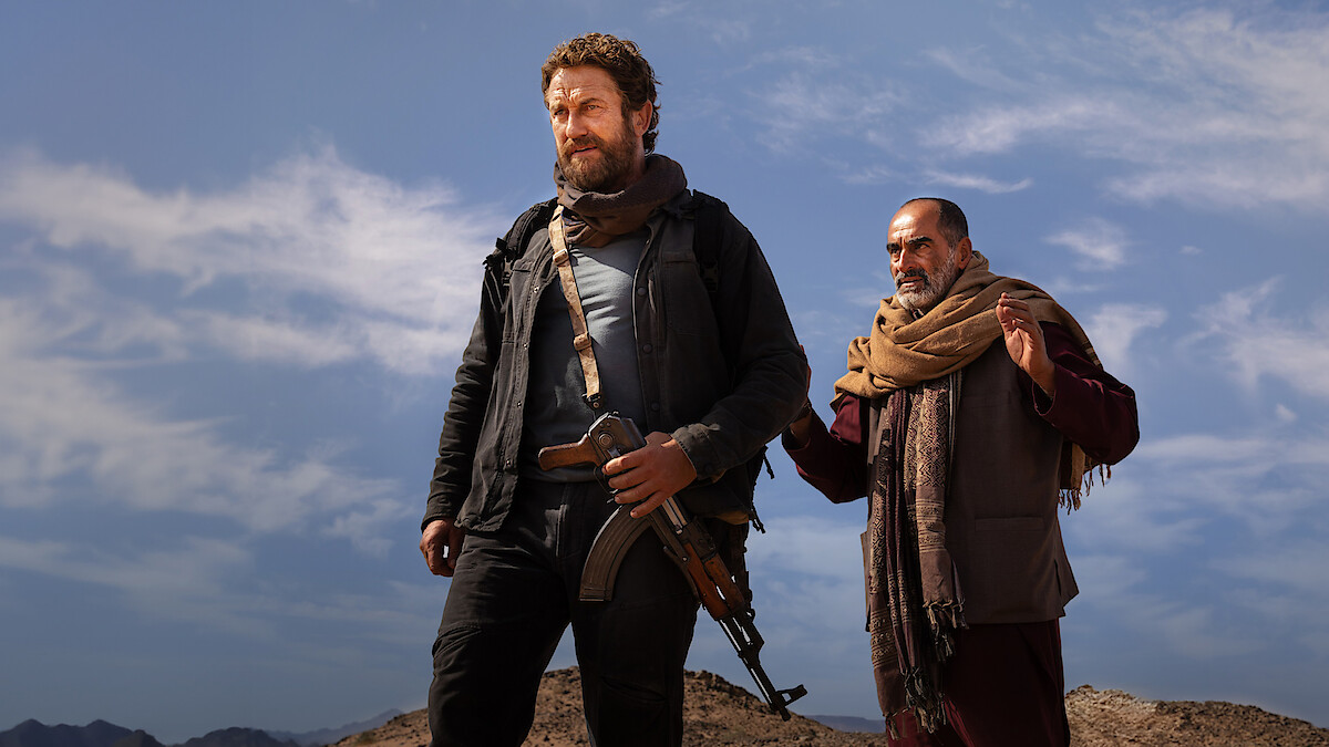 Gerard Butler stands in front of a man in an image from the movie 'Kandahar.'