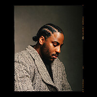 Malcolm Washington wears a patterned coat and sits in profile.