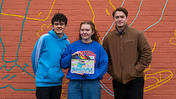 Joe Locke, Alice Oseman, and Kit Connor stand together with a 'Heartstopper' Season 3 clap board.