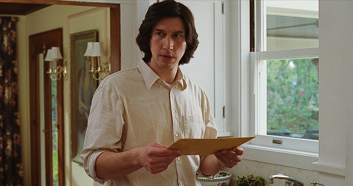 Adam Driver holding a folder while standing in a kitchen in 'Marriage Story'