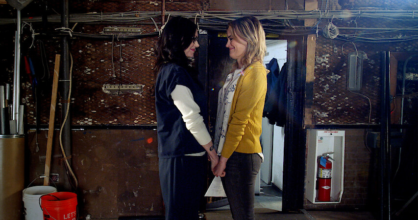 Taylor Schilling as Laura Prepon holding hands.