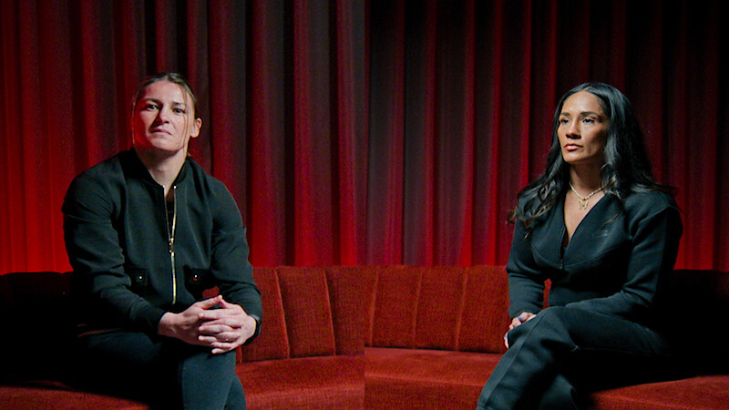 Katie Taylor and Amanda Serrano sitting on a red velvet couch