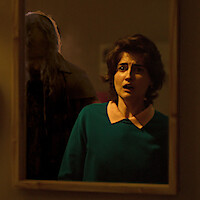 A woman is frightened by a shadowy figure in the mirror in the new series 'True Haunting.'