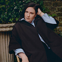 Headshot of Lena Dunham against a brick wall.