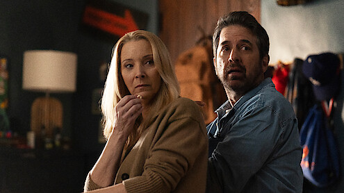 Lisa Kudrow and Ray Romano sit on a couch and look over their shoulders in Season 1 of 'No Good Deed.'