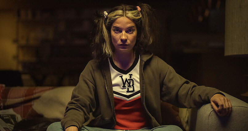 Annie Murphy as Joan from Black Mirror Season 6 sitting down.