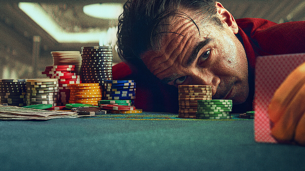 Colin Farrell as Lord Doyle laying his head on a poker table surrounded by chips.