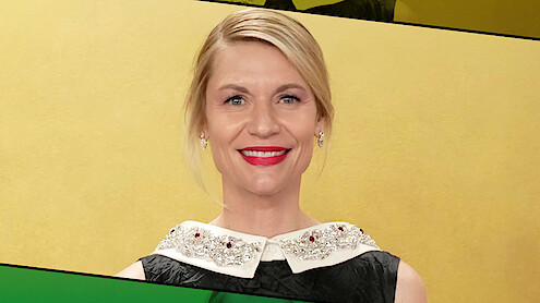 Woman with blonde hair and red lipstick smiling, wearing a black dress with a jeweled white collar, standing in front of a yellow background with green and black graphic accents.