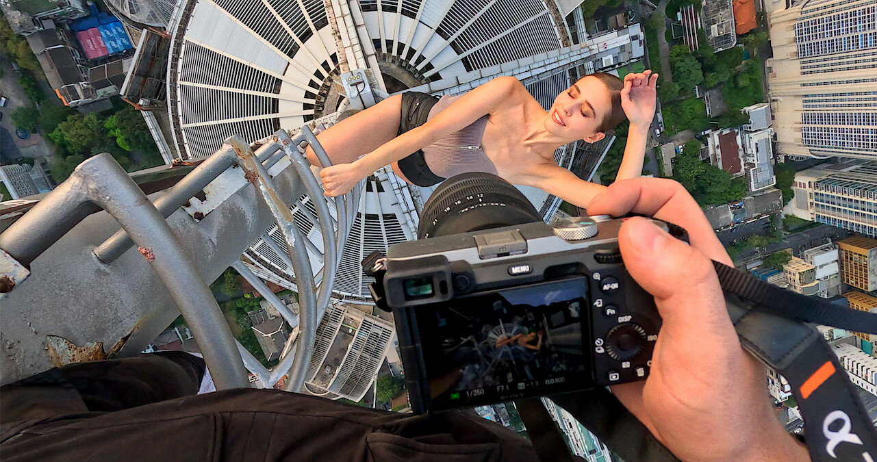 Two people kissing on a crane with a city skyline in the background