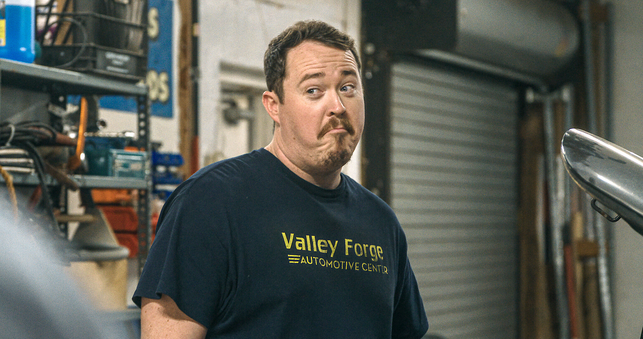 Tires - Shane Gillis standing in the shop looking innocent