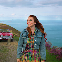 Ed Speleers and Lindsay Lohan walk along a scenic coastal path with the ocean behind them in Irish Wish.