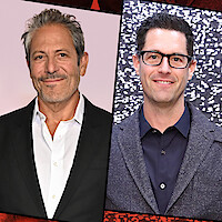 Two men in business attire, both smiling. The left man is standing in front of a pink background. The right man has dark hair, glasses, and a suit, with a black and white patterned backdrop.