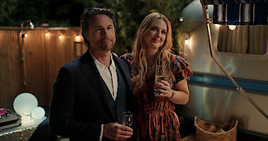  Martin Henderson as Jack Sheridan and Alexandra Breckenridge as Mel Monroe smile together at a party in Season 5 of 'Virgin River.' 