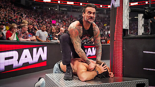 CM Punk attacks Seth Rollins outside of the ring during WWE RAW