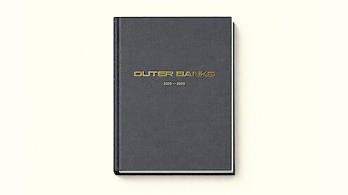 A black hardcover book with gold "Outer Banks 2020–2025" text on the cover, photographed on a plain off-white background.