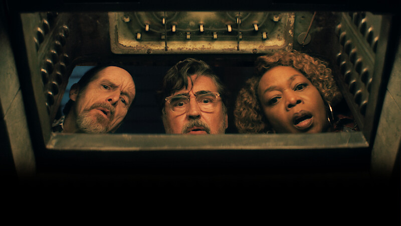 Three people peer curiously into a metal hatch or container, illuminated from below, with mechanical details visible above them, suggesting a mysterious or tense environment.
