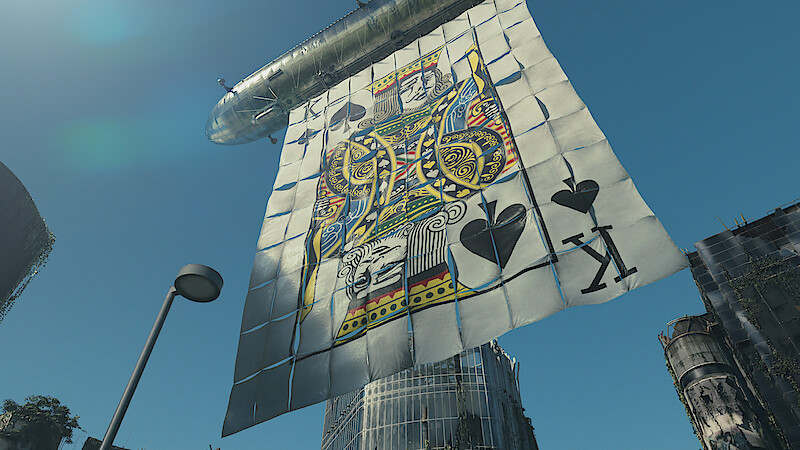 A giant King of Spades playing card banner is suspended beneath an airship, floating over a cityscape with modern and weathered buildings under a clear blue sky.