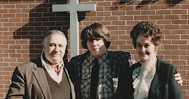 Ed Warren, David Glatzel, and Lorraine Warren standing in front of a cross.