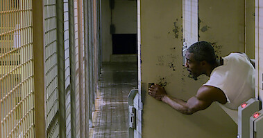 Prisoner in cell reaching outside of the bars. 