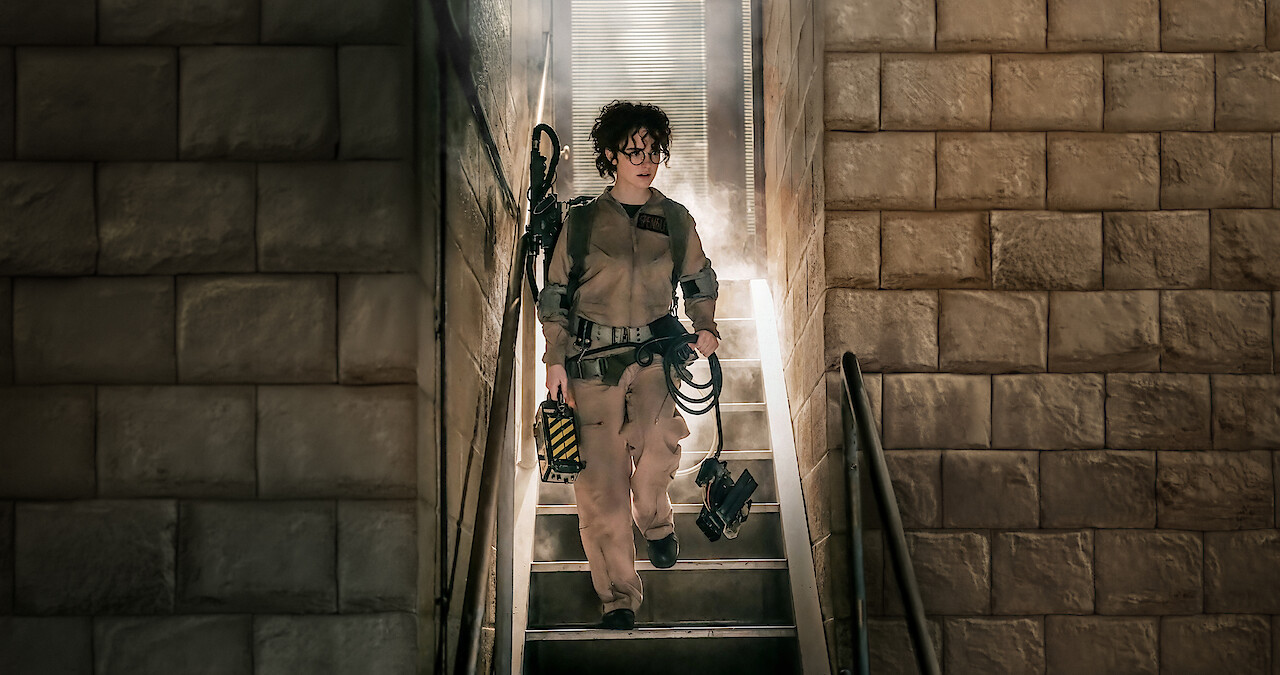 Mckenna Grace walks down a flight of stairs in a ghostbusters uniform in 'Ghostbusters: Frozen Empire'