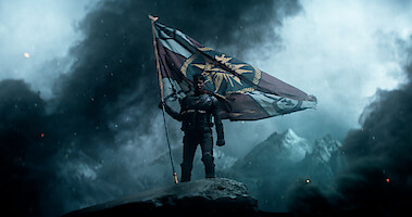 Still from the 'Rebel Moon' trailer of a man holding a flag in a mountainous landscape 
