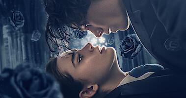 Two lovers look into each other's eyes with black roses falling around them in 'The Tearsmith.'