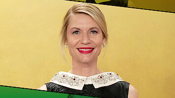 Woman with blonde hair and red lipstick smiling, wearing a black dress with a jeweled white collar, standing in front of a yellow background with green and black graphic accents.