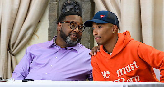EZEKIEL WILLIAMS and  PHARRELL WILLIAMS sitting at a table